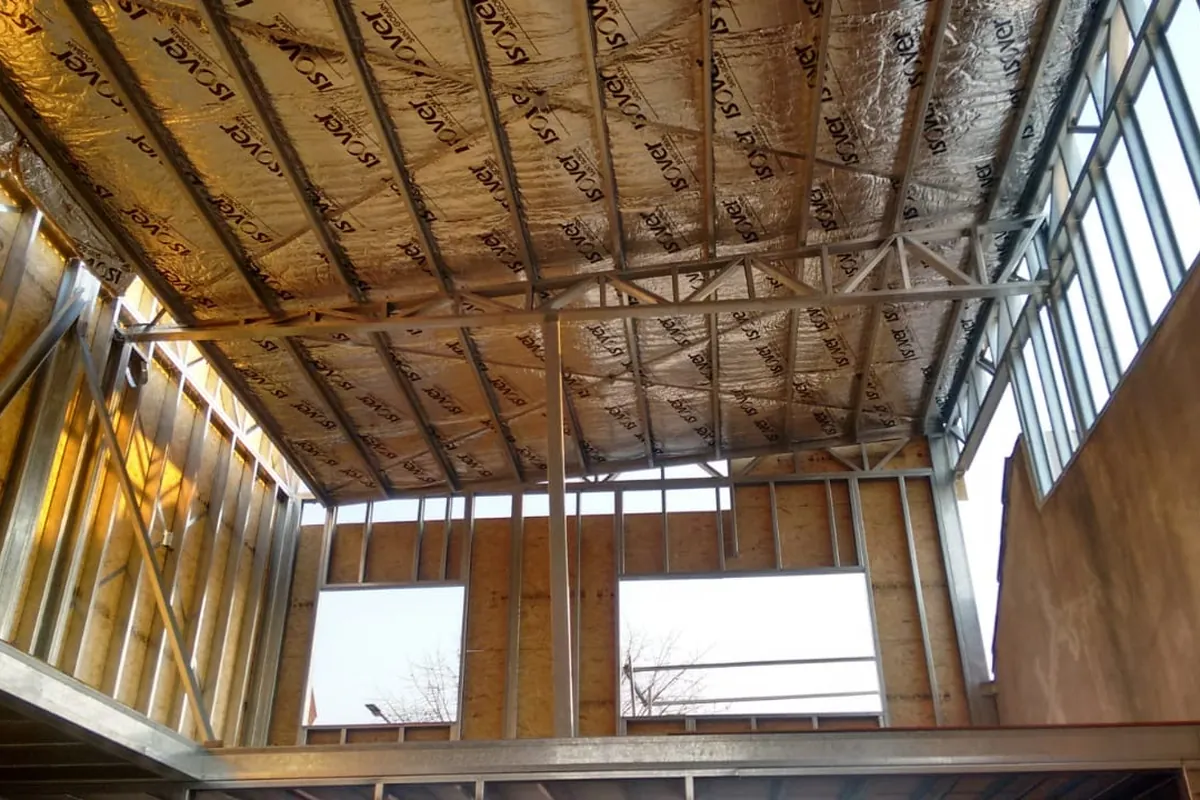 Interior de obra con estructura de techo y entramado visibles